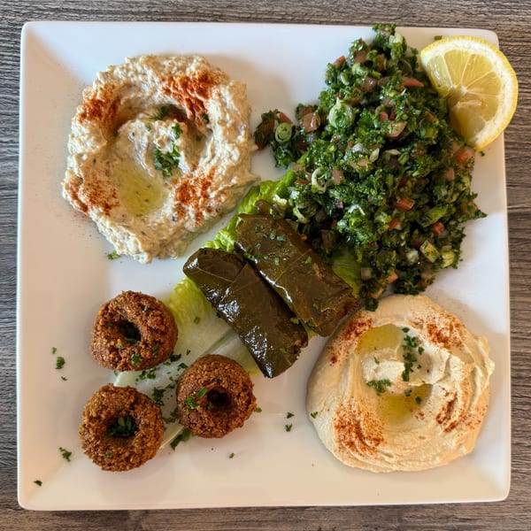 A Lebanese mezze platter with baba ghanoush, tabbouleh, stuffed grape leaves, falafel, and hummus.